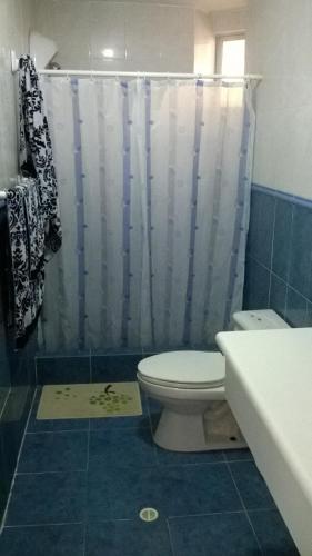 a bathroom with a toilet and a shower curtain at Departamento Torresol Tropical in Tonsupa
