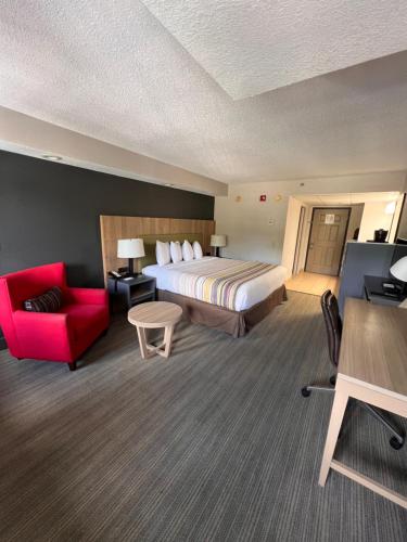 a hotel room with a bed and a red couch at Country Inn & Suites by Radisson, Pigeon Forge South, TN in Pigeon Forge
