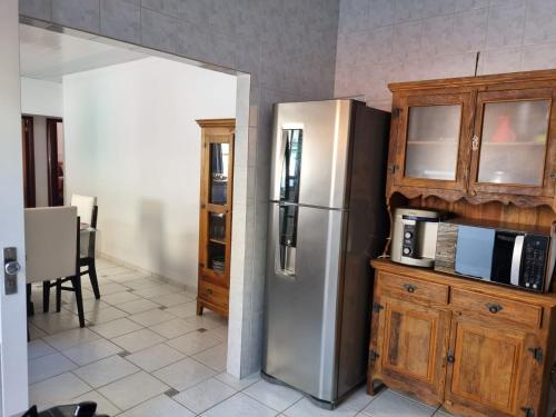 a kitchen with a stainless steel refrigerator and wooden cabinets at Casa Maciel in São Thomé das Letras