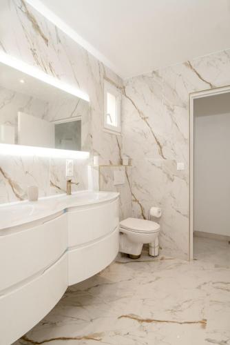 une salle de bain blanche avec un lavabo et des toilettes dans l'établissement Fourside Deluxe Apartments in Le Bourget, au Bourget