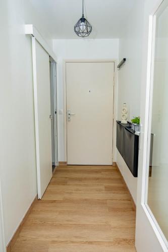 un couloir avec une porte blanche et un plancher en bois dans l'établissement Logement cosy près des sites JO, à Stains