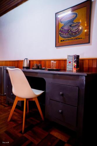 a desk with a white chair in a room at L'anis Etoilé - Hôtel Restaurant in Antsirabe