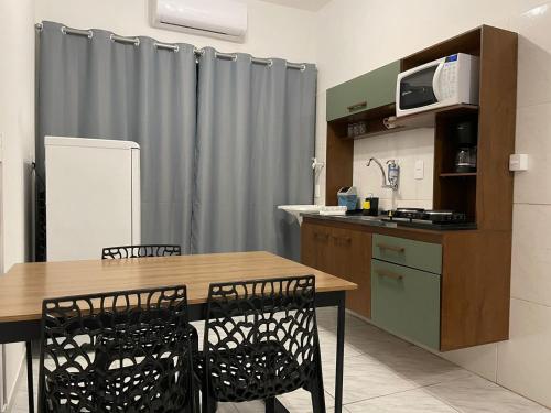 a kitchen with a table and chairs and a microwave at Villa Bilac - Amplos Studios 2km da Vila Germânica in Blumenau