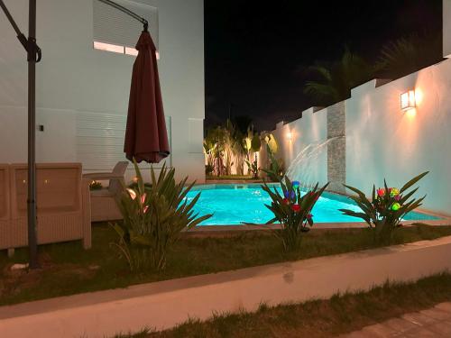 a swimming pool at night with an umbrella at Villa Nesrine in Hammamet Sud
