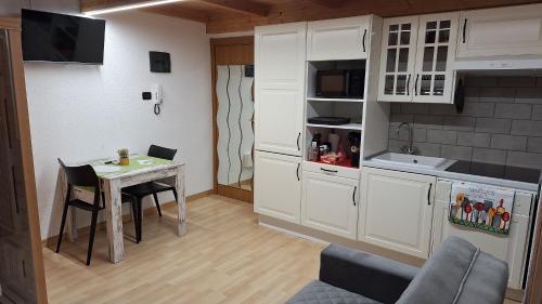 a kitchen with white cabinets and a table with chairs at Romantico - SAUNA- il tuo week end di coppia in Valtellina- in Grosio