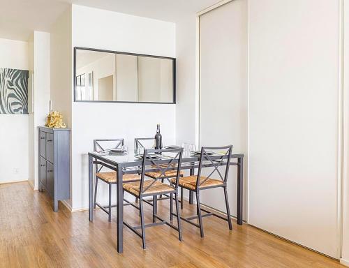 une salle à manger avec une table et des chaises noires dans l'établissement Deux pièces spacieux - Métro ligne 14 à 50m, à Saint-Ouen