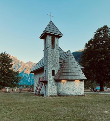 a small church with a steeple on a field at Vila Shkalla in Theth