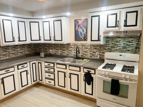 a kitchen with white cabinets and a sink and a stove at The Freedom HOME from HOME in New Bedford