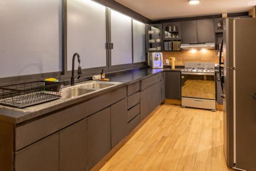 a kitchen with stainless steel appliances and a wooden floor at Posh Polanco Stay TVs and Desks in Each Room in Mexico City