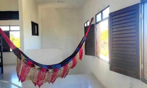 a hammock in a room with two windows at Hostel Summer Praia do Sol in João Pessoa