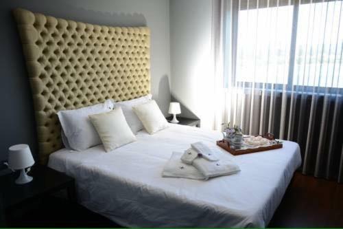 a bedroom with a large white bed with a large window at Figurino do Douro in Melres