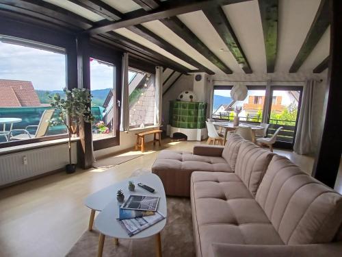 a living room with a large couch and large windows at Ferienwohnung Lodge am See - Terrasse - Kachelofen in ruhiger Lage nahe Schluchsee in Schluchsee