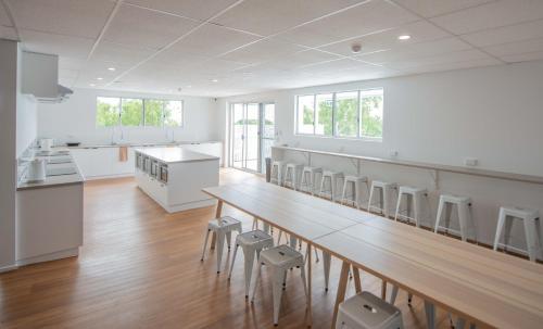 a large white kitchen with a long table and stools at Bounce Airlie Beach in Airlie Beach