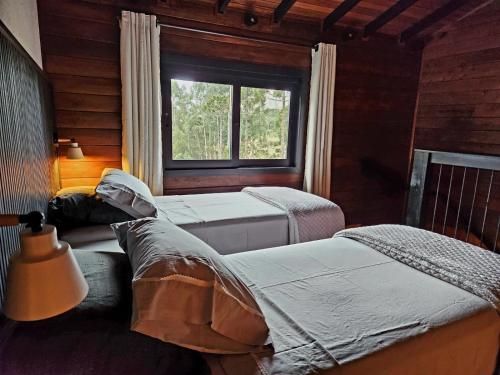 a bedroom with three beds and a window at Pousada Contos e Sonhos in Urubici