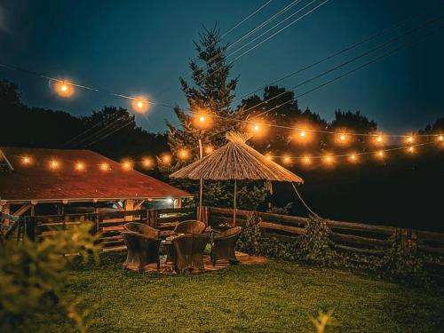 a patio with chairs and an umbrella at night at Rtanjski konak in Boljevac