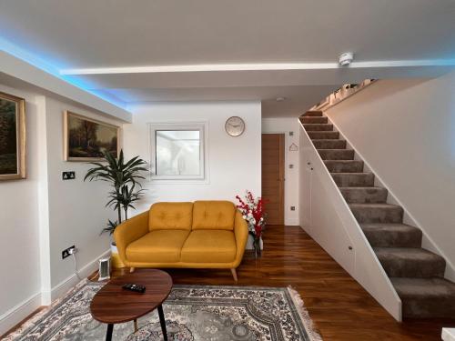 a living room with a yellow couch and stairs at Haven Homes - Central Luton Studio Apartments in Luton