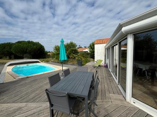 une terrasse avec une table et un parasol à côté d'une piscine dans l'établissement Maison spacieuse avec piscine privative, terrasse et jardin près des Sables-d'Olonne - FR-1-197-297, à LʼÎle-dʼOlonne
