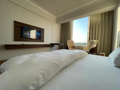 Una habitación de hotel con una cama blanca y un televisor. en Hotel Basant Sarovar, en Mathura