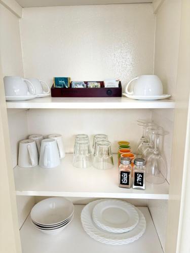 a white cabinet with plates and jars and dishes at Kowhai Motel Rotorua in Rotorua