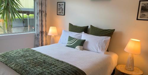a bedroom with a bed with white pillows and a window at Koru Havenz in Picton