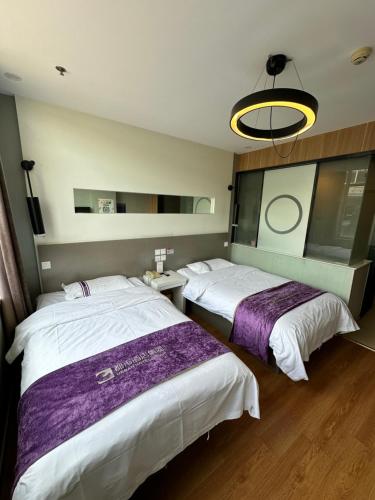 a hotel room with two beds and a chandelier at 都市118酒店广电大厦店 in Qingdao