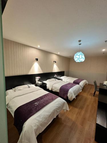a hotel room with three beds and a blue light at 都市118酒店广电大厦店 in Qingdao