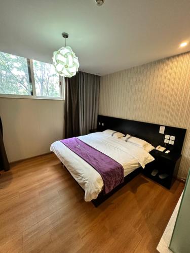 a bedroom with a large bed and a chandelier at 都市118酒店广电大厦店 in Qingdao
