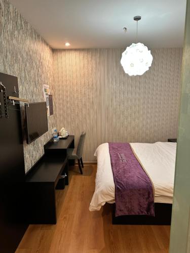 a hotel room with a bed and a desk and a lamp at 都市118酒店广电大厦店 in Qingdao