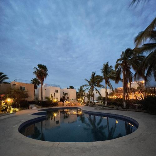 a swimming pool at night with palm trees and buildings at Casa de Susie in Cabo San Lucas