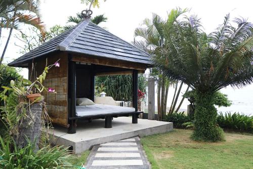 a small gazebo with a bed in it at The Villa Pantai in Temukus