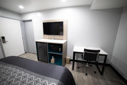 a bedroom with a bed and a desk and a tv at Express Inn & Suites Ontario Airport in Ontario