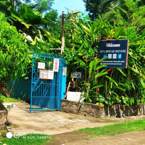a blue gate with a sign next to some plants at Sun House Rental in Mambajao