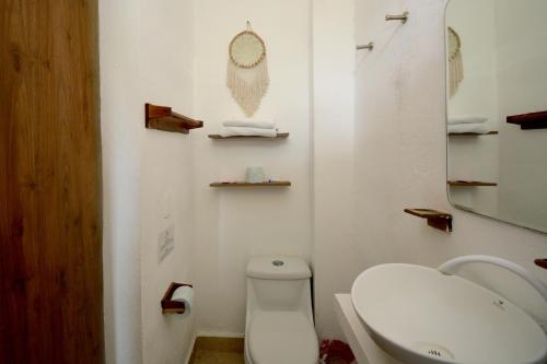 a bathroom with a white toilet and a sink at Casa Delia Hotel Downtown in Bacalar