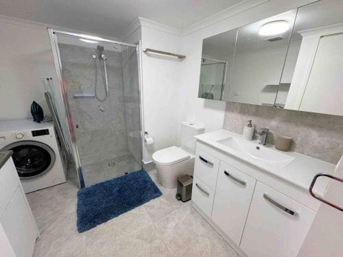 a bathroom with a shower and a toilet and a sink at Spacious Apt with pool & parking in Brisbane
