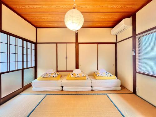 two beds in a room with wooden ceilings and windows at Spacious Beach Home 350m to Sotoura Beach in Shimoda