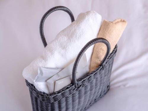 a basket filled with white towels on a bed at Tosei Hotel Cocone Tsukiji Ginza Premier in Tokyo