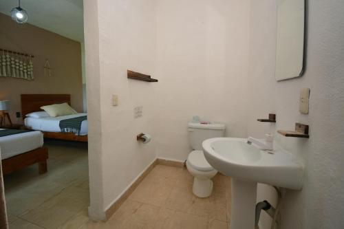 a bathroom with a toilet and a sink and a bed at Casa Delia Hotel Downtown in Bacalar