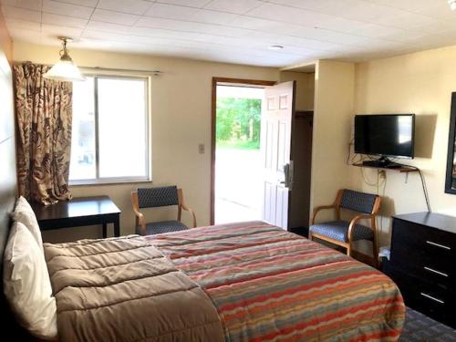 a hotel room with a bed and a television at Gratiot View Motel in Saginaw