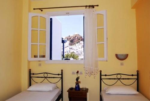 two beds in a room with a window at La Luna in Ios Chora