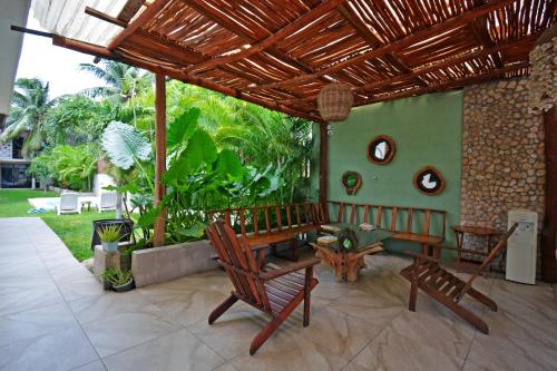a patio with chairs and a table and a wooden roof at Casa Delia Hotel Downtown in Bacalar