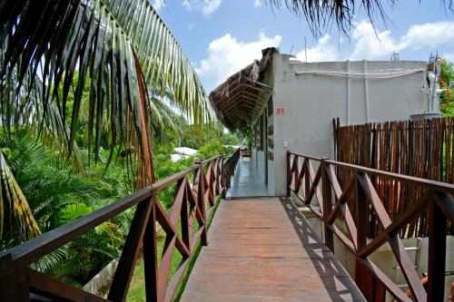 a wooden walkway leading to a building with palm trees at Casa Delia Hotel Downtown in Bacalar