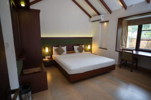 a bedroom with a bed and a desk and a window at Misty Grove Resort Hotel in Gūdalūr