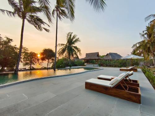 a resort swimming pool with two lounge chairs next to it at Full Moon Island Resort in Kaoh Sdach