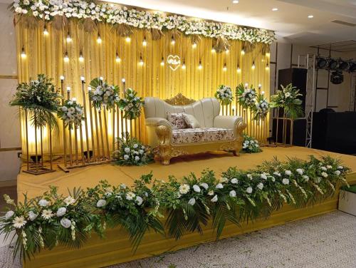 a stage with a couch and a bunch of flowers at Hotel MASAGA by QCENT in Gurgaon