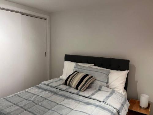 a bed with a blue and white blanket and pillows at Peaceful and convenient in Auckland