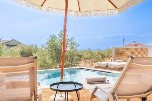 a swimming pool with two chairs and an umbrella at Petradi Suites in Kalamata