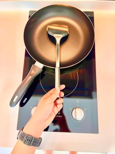 a person holding a frying pan on a stove at Legoland-3mins Drive KUROMI FAMIY SUITE in Iskandar Puteri