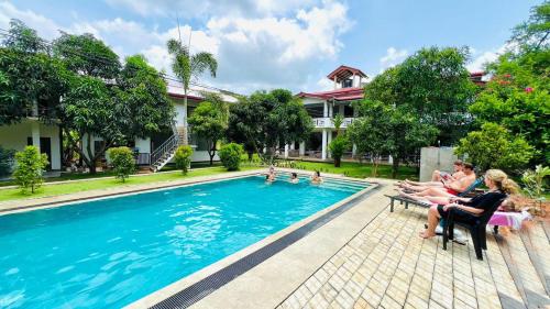 a group of people sitting around a swimming pool at Sigiriya Sun Shine Villa in Sigiriya
