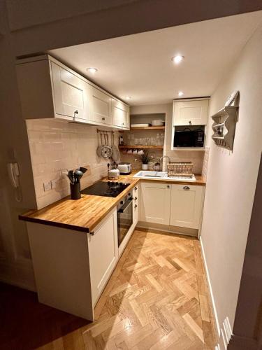 a kitchen with white cabinets and a wooden floor at Clifton Apartment in Bristol