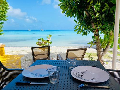 a table with plates and glasses on the beach at Jeannine Lodge in Avatoru